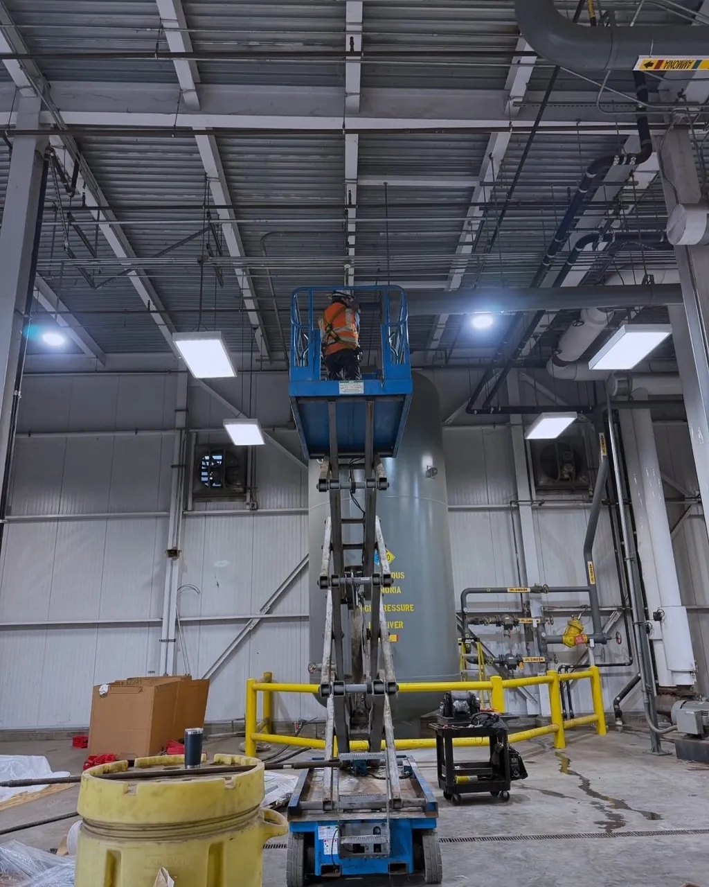 Technician on a scissor lift working above an anhydrous ammonia high-pressure receiver