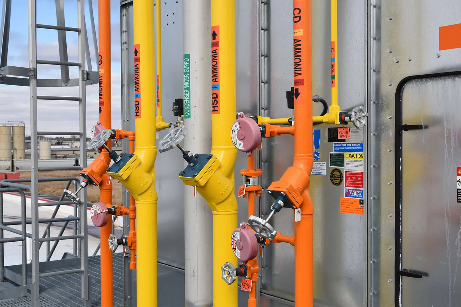 Color-coded orange and yellow ammonia transfer piping with hand valves on a plant rooftop during an ammonia transfer